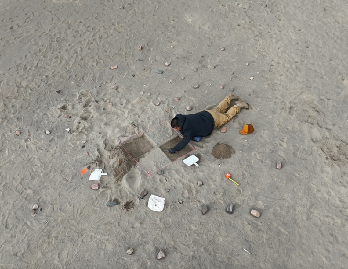 Vue aérienne d’un homme allongé sur le sable, creusant dans des quadrants de sable.