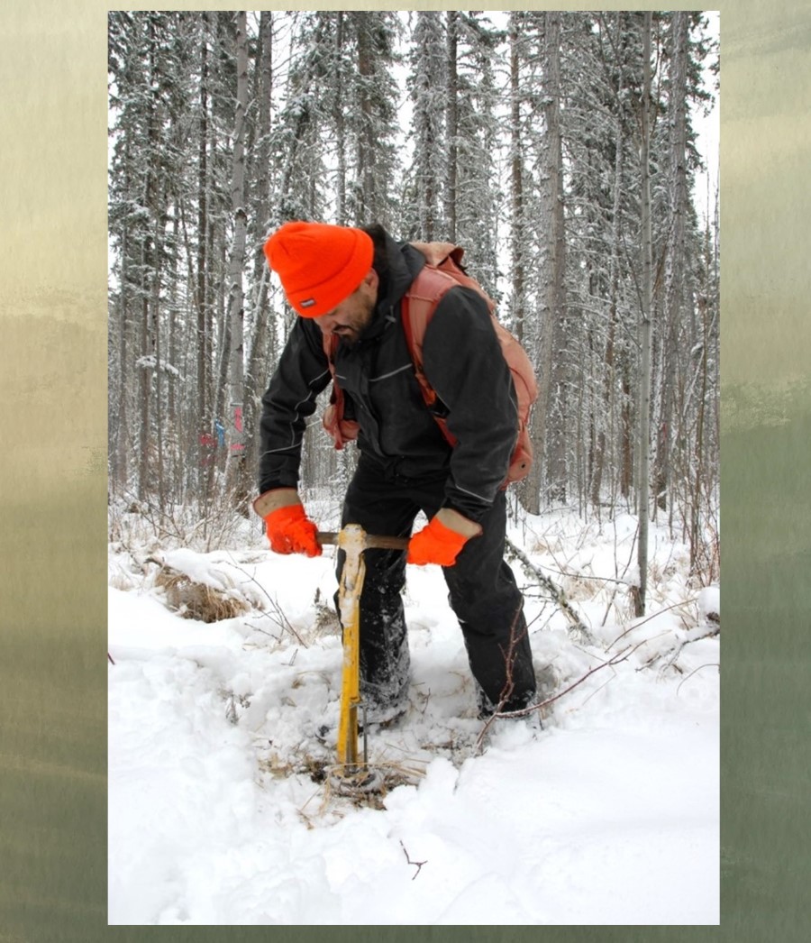 Photo d’un homme debout en train de percer un trou dans la forêt enneigée.