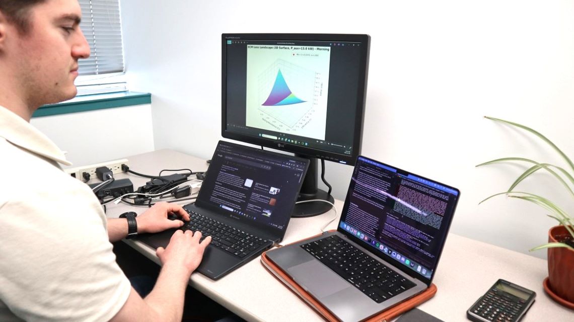 Assis à un poste de travail, un scientifique analyse des données sur plusieurs écrans d’ordinateur.