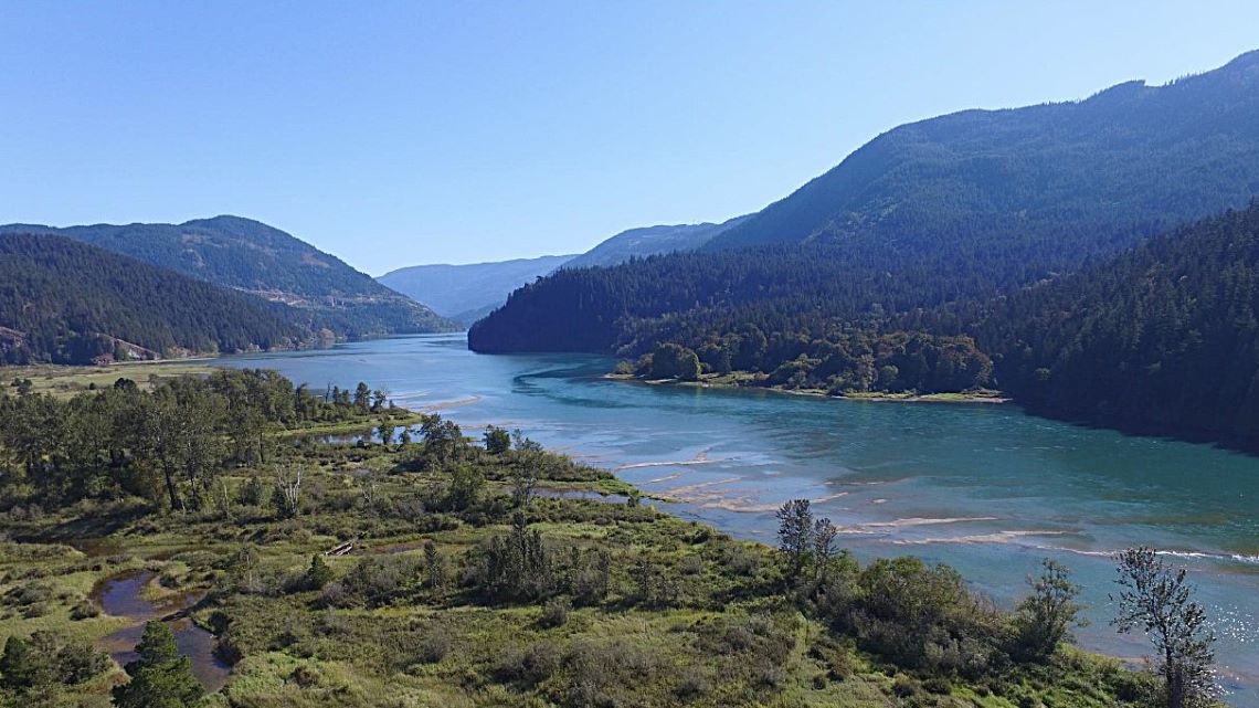 Vue aérienne panoramique du bassin versant de Harrison, avec des arbustes au premier plan et des montagnes basses en arrière-plan.