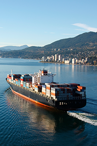 Un cargo naviguant sur l’océan avec une ville en arrière-plan.