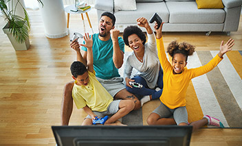 Famille assise ensemble sur le sol en train de jouer à des jeux vidéo