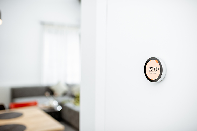 Thermostat intelligent rond avec écran tactile installé sur un mur à l’intérieur.