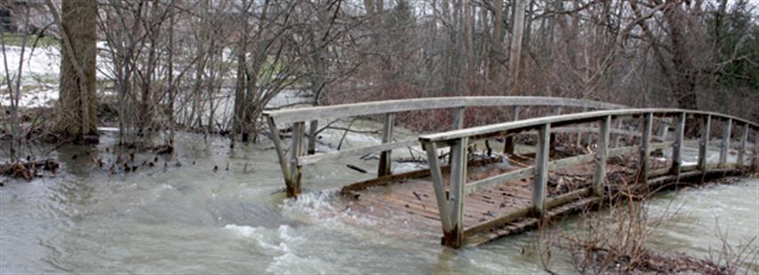 photographie d’un pont piétonnier de bois submergé par les eaux, à London, en Ontario