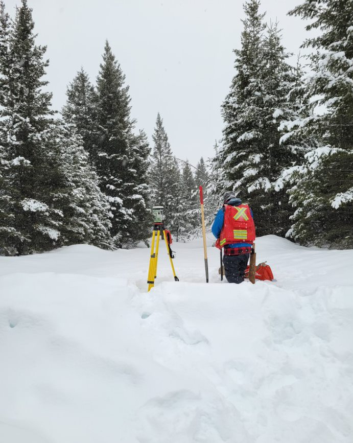 Une personne debout dans la neige avec de l'équipement d'arpentage