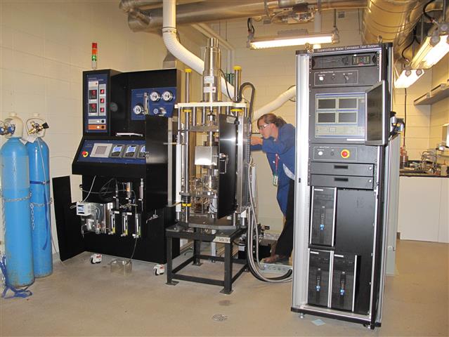 Une femme utilisant une machine dans un laboratoire de corrosion à haute température et haute pression.